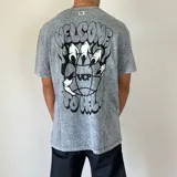 Remera de algodón con efecto lavado ácido, corte semi oversize y estampa gráfica en la espalda con el texto 'Welcome to Hell' y un diseño de garras sobre un globo terráqueo.