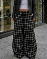 Pantalón de corte amplio y holgado con diseño a cuadros, cintura elástica con cordón ajustable y bajos regulables en las piernas.