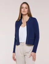 Cardigan corto azul marino de punto, con silueta entallada y largo a la cintura. Cuenta con un ribete decorativo que recorre el cuello redondo y la abertura frontal, integrando una cadena dorada en contraste. Posee bolsillos delanteros simulados y mangas largas.