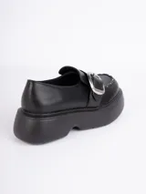 Zapatos tipo mocasines negros con plataforma de 6cm, hebilla metálica plateada y pequeños detalles plateados en la capellada.