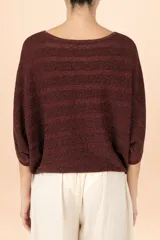 Suéter de punto con acabado metalizado, color café, con diseño de rayas horizontales texturizadas. Presenta cuello barco, mangas tipo murciélago y un bajo ajustado.