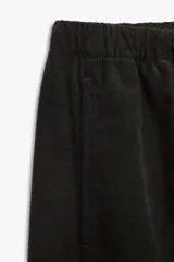 Pantalón de tiro alto con pernera ancha, confeccionado con cintura elástica ajustable mediante cordones. Cuenta con bolsillos laterales y bolsillos de plastrón en la parte posterior.