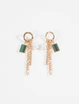 Aros colgantes dorados con diseño de argolla superior y múltiples dijes colgantes: una cadena de eslabones, una tira de strass, una perla pequeña y un dije rectangular de piedra verde.