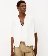 Camisa masculina Marfinno de corte boxy y manga corta, confeccionada en puro lino color blanco. Presenta cuello bowling y cierre frontal con botones.