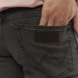 Pantalón de jean de corte slim, color gris oscuro, con bolsillos delanteros y traseros.