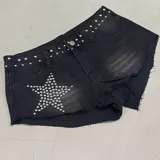 Short de denim negro con efecto deslavado, tiro medio y botamanga deshilachada. Presenta tachas metálicas plateadas decorativas en la pretina y un diseño de estrella formado por tachas en el bolsillo delantero.