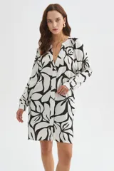 Camisa tipo vestido de viscosa con estampado floral abstracto en blanco y negro, cuello en V con botonera frontal completa, mangas largas abullonadas y diseño holgado.