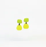 Caravanas colgantes artesanales compuestas por dos piezas de resina en tonos verde lima, unidas por un eslabón negro. Diseño moderno y minimalista con acabado mate.