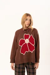 Buzo de punto color chocolate con diseño de flor grande en el frente en tonos rojos y centro texturizado en color crema. Presenta cuello redondo, mangas largas y puños y ruedo acanalados.