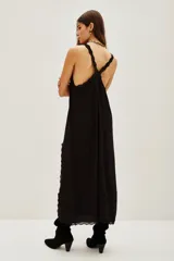 Vestido largo negro de viscosa con escote en V, tirantes finos, detalle de encaje en el escote y en la abertura lateral de la falda.