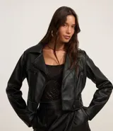 Campera biker cropped confeccionada en cuero sintético negro, con cierre cruzado con cremallera, cuello con solapa, pespuntes contrastantes y bolsillos con cremallera.
