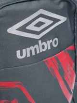 Mochila negra con diseño gráfico abstracto en azul vibrante y logo Umbro en azul. Posee bolsillo lateral de malla para botella y tiradores de cierre azules.