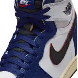 Zapatillas Nike Air Jordan 1 Retro High de caña alta, confeccionadas en cuero de color blanco, azul y detalles en negro. Cuentan con el logotipo de las alas en el lateral del tobillo, el swoosh de Nike en color negro y suela de tono envejecido.