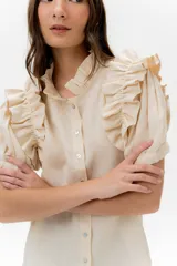 Camisa celeste de lino con cuello mao y mangas cortas abullonadas con volados. Cierre frontal con botones.