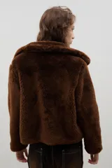 Campera corta de piel sintética en color crema, con cuello amplio tipo solapa y cierre frontal.