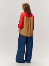 Camisa de lino color blanco con detalles combinados en tonos beige, cuello camisero, cierre frontal con botones oscuros y mangas largas con puños en contraste.