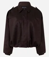 Campera bomber de gamuza sintética color marrón oscuro, con cuello clásico, cierre frontal, hombros caídos y puños ajustados. Presenta un diseño holgado con textura aterciopelada.