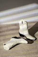 Bota de cuero negra con caña media, punta fina y taco bloque. Diseño estilo western con bordados decorativos.