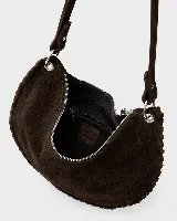 Bolso de mano tipo sobre confeccionado en gamuza color marrón, con diseño de bordes trenzados y detalle de flecos largos laterales. Incluye herrajes metálicos plateados y correa desmontable.