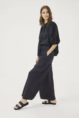 Pantalón culotte negro de lino orgánico, con cintura alta, diseño plisado y bolsillos laterales.