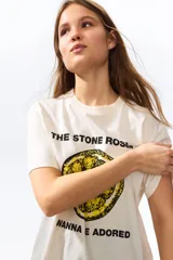 Remera de punto suave de algodón, color beige, con hombros ligeramente caídos y cuello redondo ribeteado acanalado. Cuenta con estampa frontal de la banda The Stone Roses con ilustración de un limón y texto.