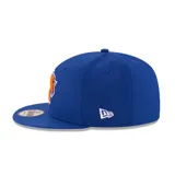 Gorro New Era azul con visera plana, logo de los New York Knicks bordado en el frente y cierre snapback ajustable.
