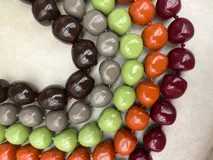 Collar de diseño artesanal compuesto por múltiples hileras de cuentas de resina pulida en una paleta de colores vibrantes que incluye tonos marrones, grises, verdes, naranjas y bordó.