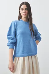 Sweater de tejido liviano con silueta relajada, hombros caídos y mangas largas con puños ajustados. Presenta cuello redondo y lazos ajustables en el bajo.