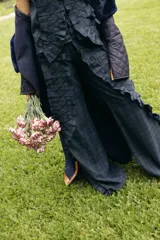 Pantalón de corte amplio con estampado de cuadros escoceses en tonos azul y verde. Presenta apliques de tela plisada con costuras decorativas en zigzag a lo largo de las piernas, tajos laterales y bolsillos funcionales.