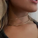 Gargantilla doble dorada, rígida, de metal.