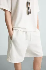 Bermuda de algodón gris con efecto lavado, corte relajado, cintura elástica ajustable con cordón y bolsillos laterales y trasero de vivo.