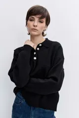 Sweater de punto negro con cuello polo y cierre frontal de botones, de manga larga y calce holgado.