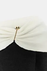 Top de punto color crema con escote recto estilo hombros descubiertos, manga larga y detalle de hebilla metálica en el hombro.