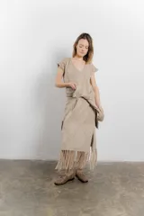 Vestido largo tejido color beige, con diseño en bloques de rombos, escote en V y flecos en el ruedo.