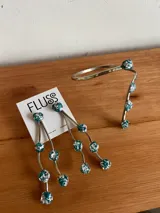 Caravanas colgantes de bronce con diseño de tres hilos ondulados, adornados con pequeñas piedras turquesas con incrustaciones plateadas. Incluye un brazalete a juego con el mismo diseño de piedras.