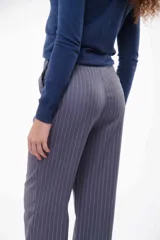 Pantalón de vestir color visón con finas rayas verticales blancas, corte recto, cintura alta con elástico y detalle de botones en el ruedo.