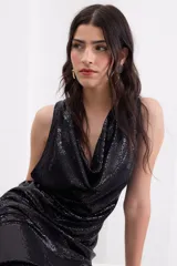 Vestido largo negro de crepe elástico con brillo, sin mangas, con escote drapeado y corte recto y fluido.