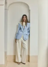 Blazer celeste de corte recto, con cuello de solapa con muesca, manga larga, bolsillos laterales con solapa y cierre frontal de un botón.