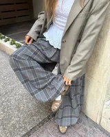 Pantalon de corte amplio con diseño a cuadros en tonos gris, blanco y naranja. Presenta cintura elástica con cordón ajustable y detalle de tiras en la botamanga para fruncir.
