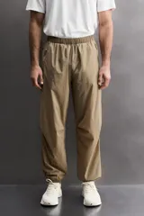Pantalón jogger de corte regular confeccionado en tejido técnico ligero, con cintura elástica, bolsillos laterales con cierre y puños elásticos en los tobillos.