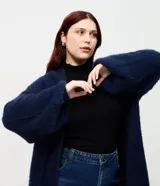 Cardigan abierto de punto pesado con textura peludita, manga larga y diseño alargado. Prenda versátil de corte holgado.