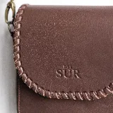 Mini cartera bandolera de cuero, de formato compacto y diseño atemporal con solapa frontal y costuras artesanales decorativas en el borde. Cuenta con el logotipo de la marca grabado en la parte delantera y correa larga regulable.