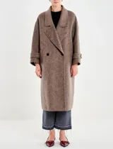 Tapado largo de paño texturado color gris topo, de corte oversize y doble botonadura. Presenta cuello con solapas anchas y mangas largas con puños doblados.