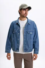 Campera de jean de hombre, color azul claro lavado, con cuello camisero, botones frontales y bolsillos con tapa en el pecho. Presenta un calce holgado.