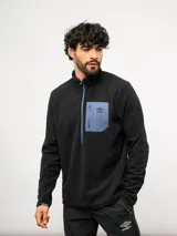 Buzo de entrenamiento Umbro con medio cierre frontal, cuello alto y bolsillo en el pecho de nylon con cierre. Presenta una textura sutil en el tejido y logo de la marca estampado en el bolsillo.