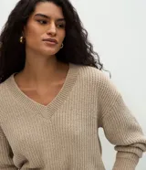 Suéter de punto color beige con escote en V, mangas largas con puños ajustados y diseño holgado. Confeccionado en poliéster.