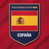 Camiseta de fútbol roja con detalles en amarillo y azul marino en cuello y mangas. Presenta un patrón geométrico sutil en el frente, el logo de la FIFA World Cup 26 y el escudo de la selección de España.