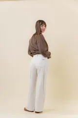Jean wide leg de tiro alto en color crudo, con pierna amplia y costuras al tono. Cuenta con cierre frontal con botón, presillas en la cintura y bolsillos traseros clásicos.