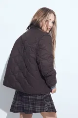 Campera acolchada de color negro con diseño capitoneado, cierre frontal con botones y cuello clásico.