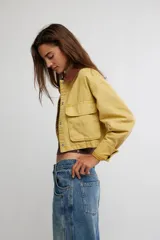 Campera corta de sarga de inspiración workwear, color amarillo con cuello en contraste marrón, bolsillos con solapa en el pecho y cierre frontal con botones.